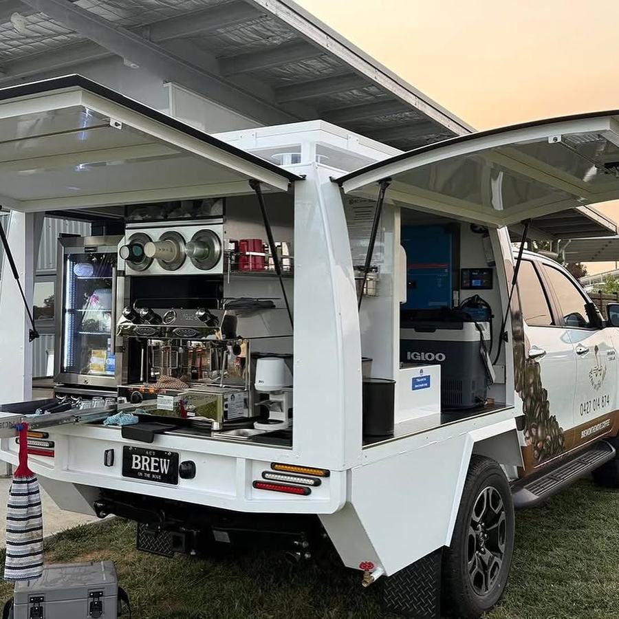A ute tray built out as a coffee bar, canopy open over the machine.