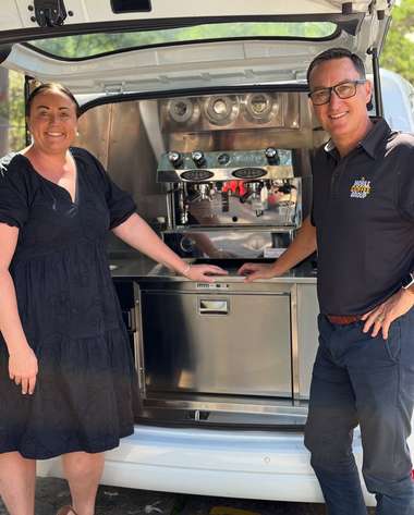 Two operators standing either side of the open rear of their coffee van.