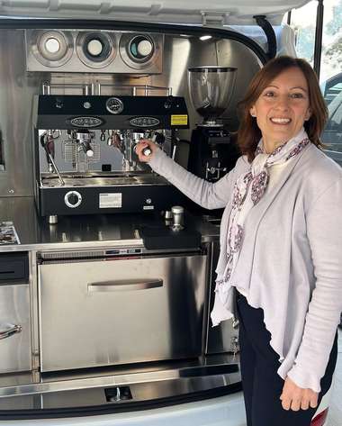 An operator resting a hand on the espresso machine inside her fitted-out van.