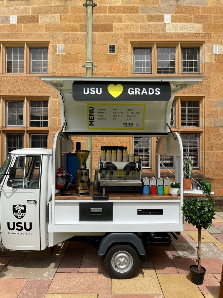 White Piaggio Ape branded for a university graduation event