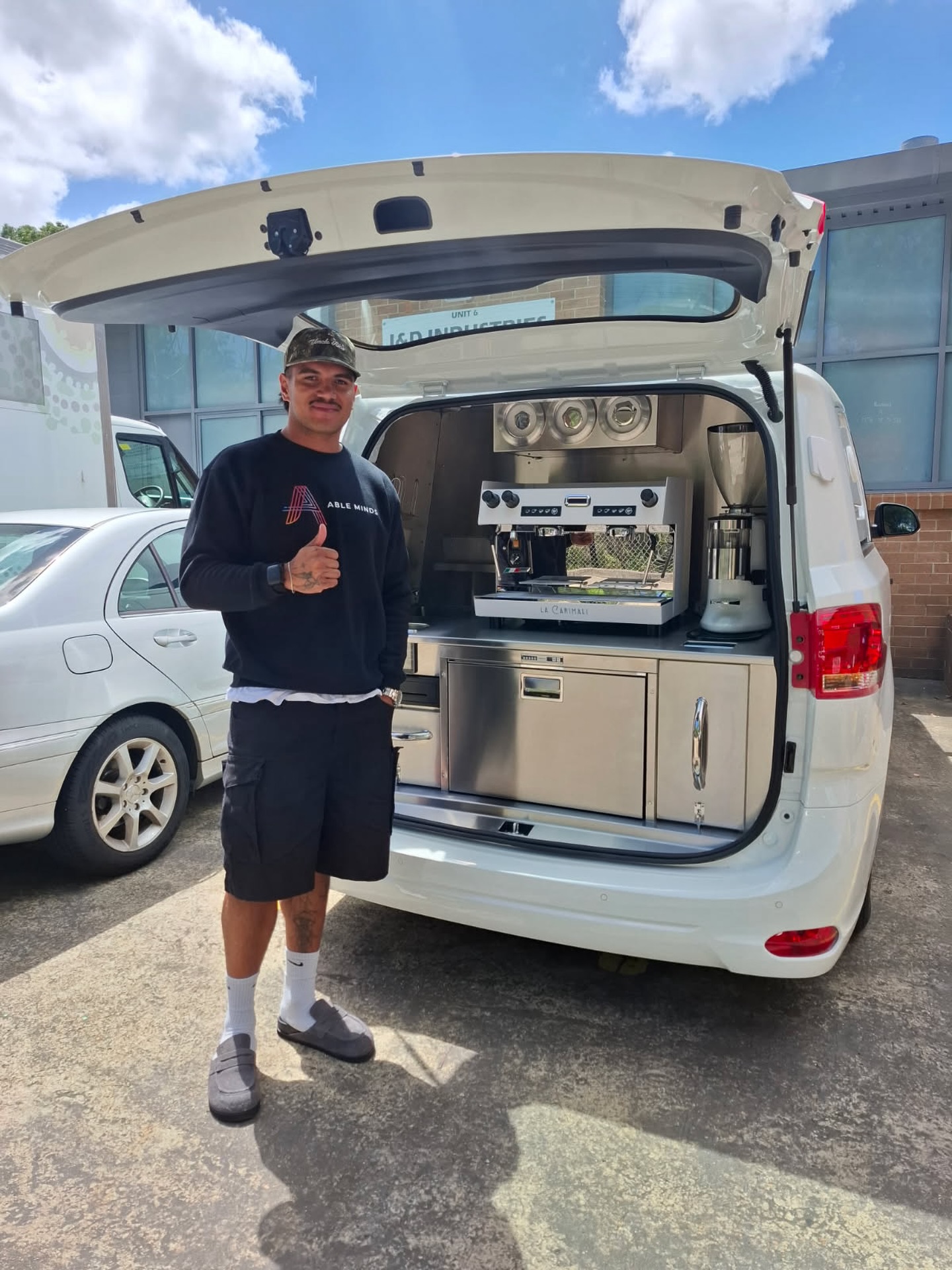 White minivan rear hatch, stainless espresso set-up, operator with thumbs up
