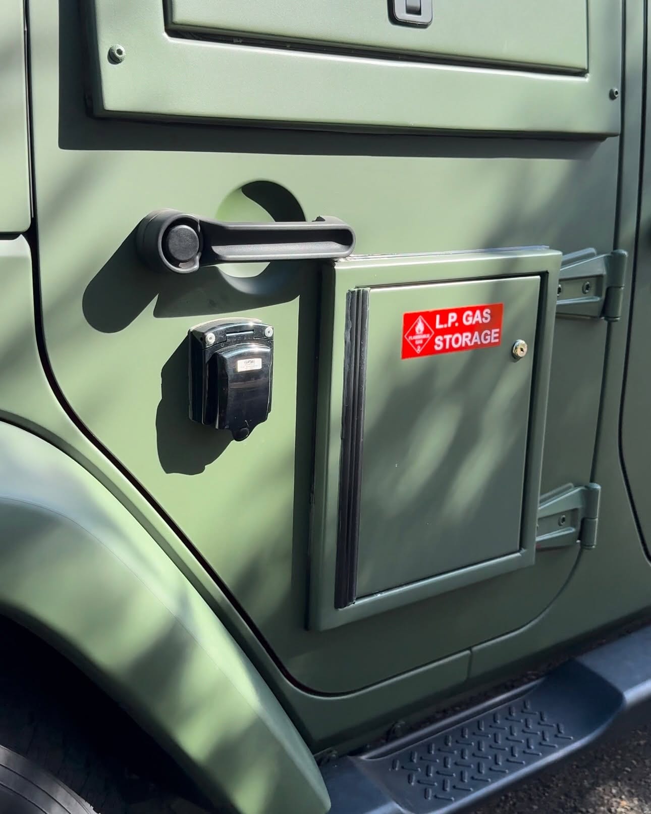 A lockable gas hatch let into the Jeep's rear quarter, labelled L.P. Gas Storage, beside an external power inlet.