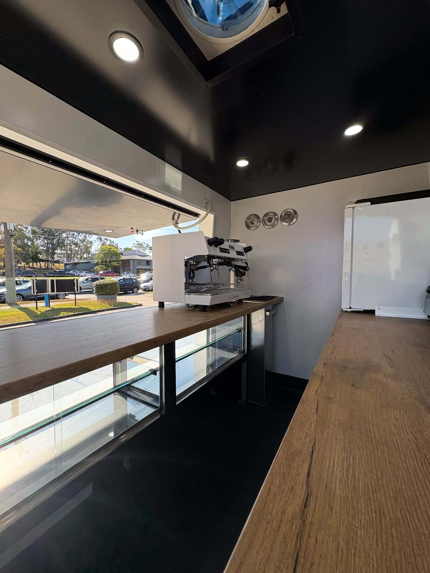 Inside a walk-in coffee van, timber bench and espresso machine